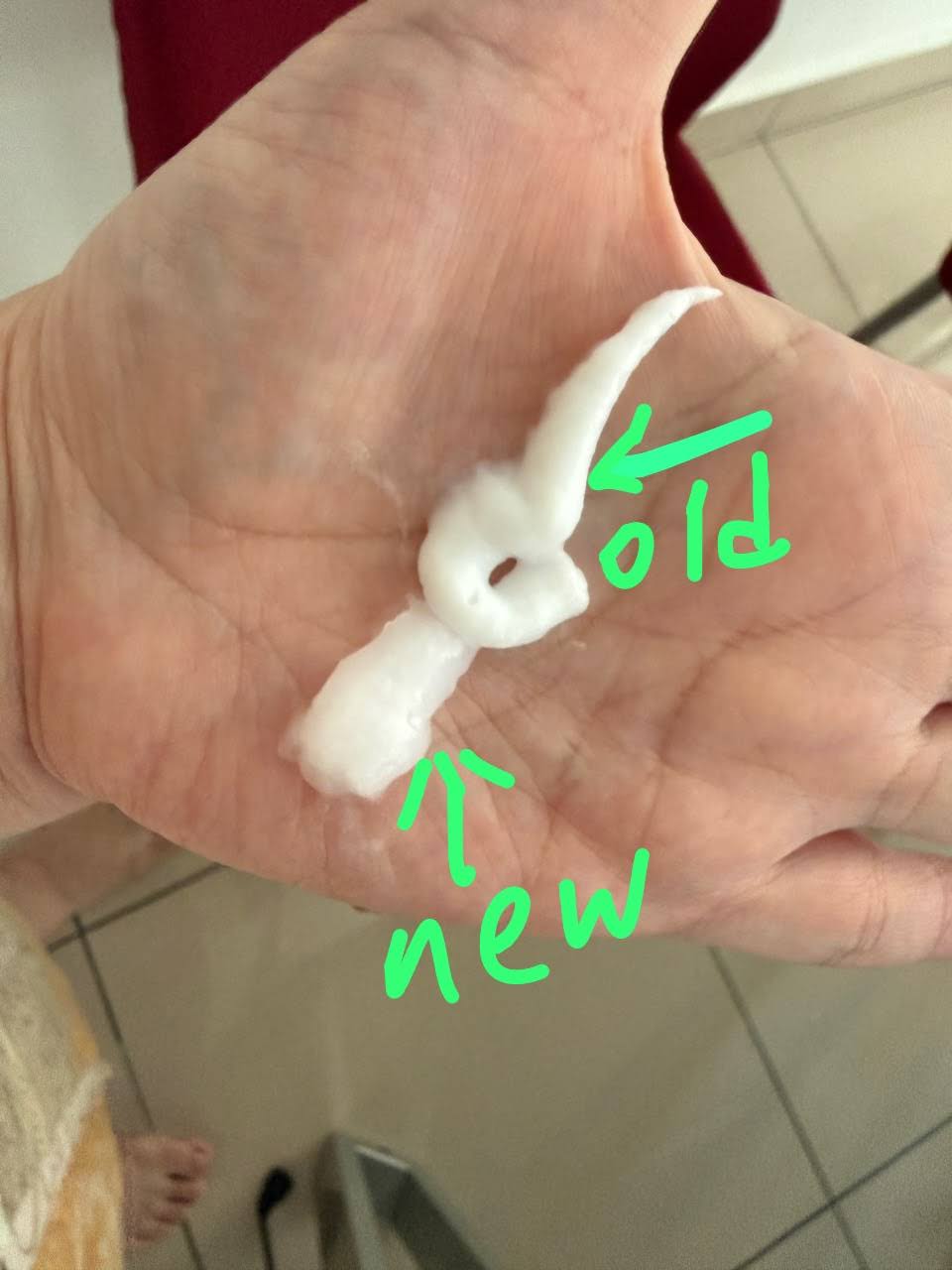 Hand holding two samples of white cream, digitally labeled with green arrows as "old" and "new" to compare product texture.