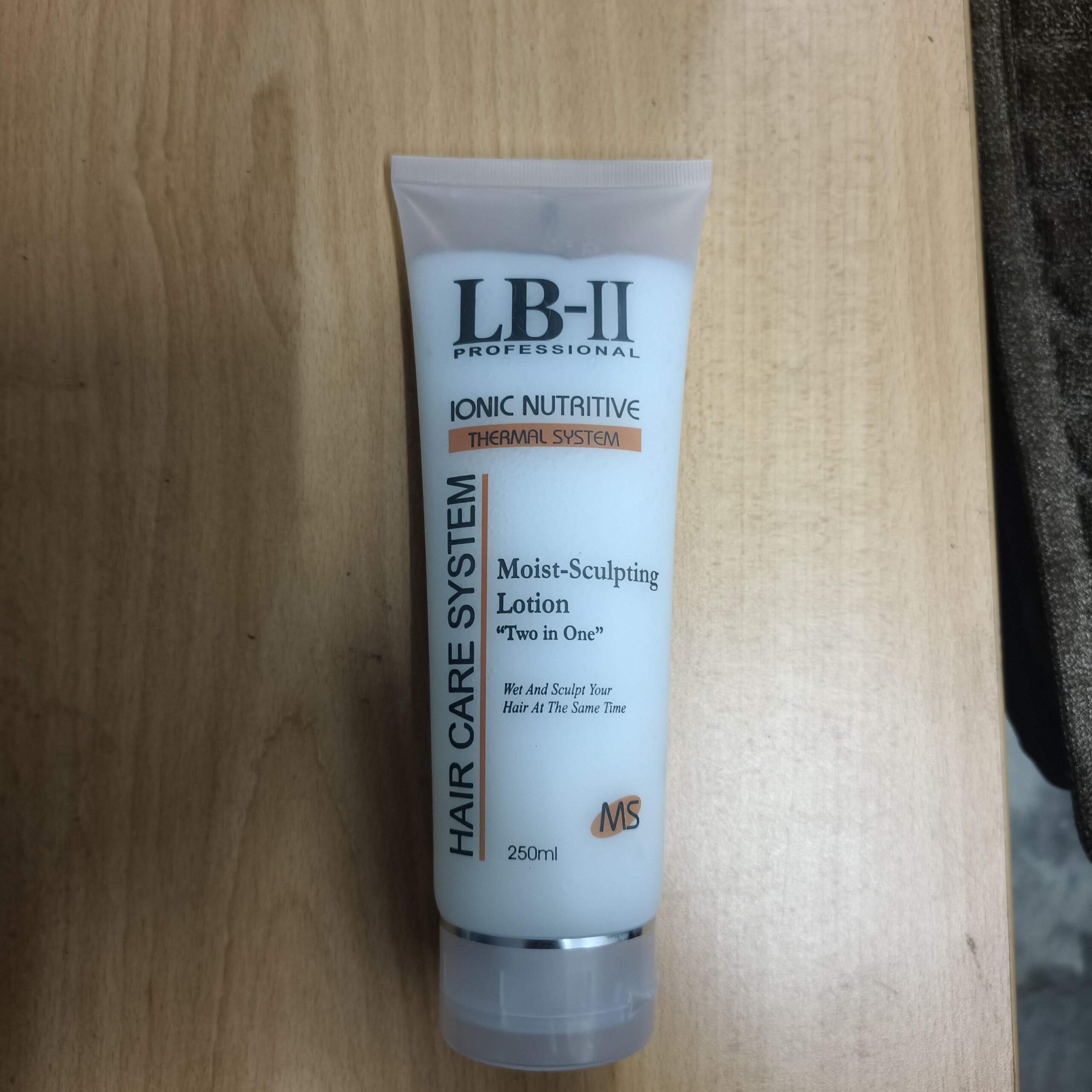 LB-II Professional Moist-Sculpting Lotion 250ml white squeeze tube resting on a light wooden surface.